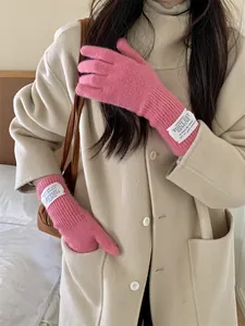 Detail view of pink knitted warm touchscreen gloves worn with a stylish beige winter coat