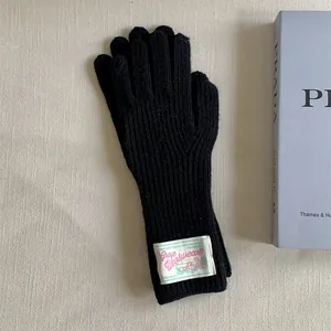 Detail view of black knitted wool gloves featuring a stylish vintage fabric label