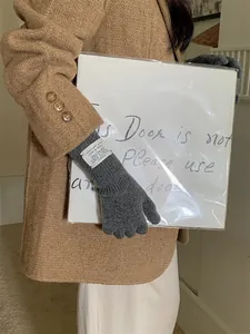 Close-up view of premium grey knit gloves for women featuring a minimalist wrist label