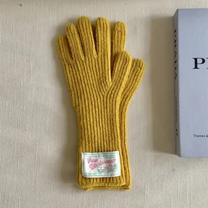 Detailed macro view of mustard yellow knitted wool gloves with a decorative fabric patch