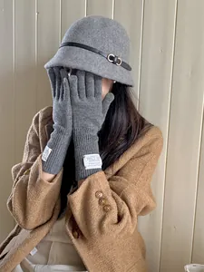 Detailed view of grey knitted touchscreen gloves worn with a stylish wool bucket hat