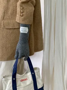 Close-up of grey knitted gloves for women with a vintage style brand label on the long cuff.