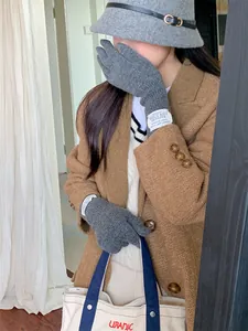 Detailed view of gray knitted wool-like gloves worn by a model in a warm autumn outfit