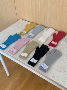 Selection of colorful knitted wool gloves with vintage fabric labels displayed on a table