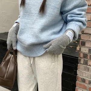Warm grey knit wool gloves featuring a stylish fabric label for cozy winter fashion wear.