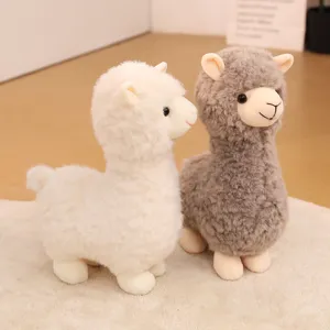 Adorable white and grey stuffed alpaca plush toys sitting on a soft white rug in a room