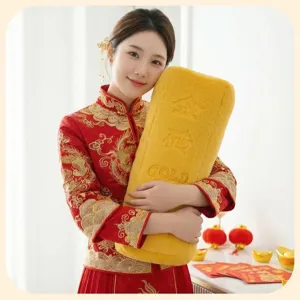 Modèle asiatique tenant un oreiller créatif en peluche de lingot d'or en habit rouge