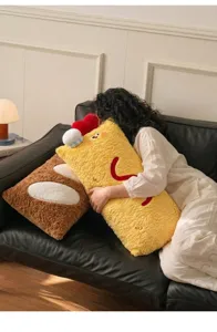 Gros plan d'un mignon coussin en peluche crevette tenu par une personne sur un canapé