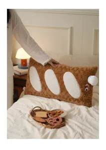 Gros plan d'un grand oreiller en peluche baguette avec un visage mignon sur un lit douillet.