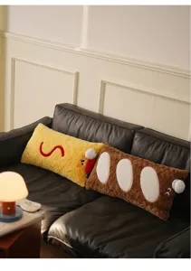 Gros plan d'oreillers décoratifs en peluche en forme de crevette et baguette sur un canapé