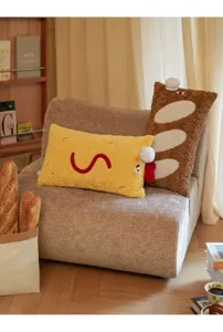 Vue détaillée de coussins créatifs en forme de crevette et baguette sur un fauteuil gris