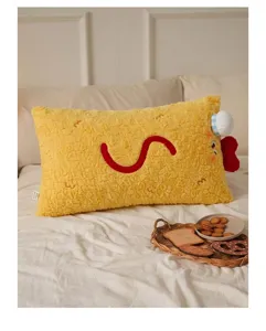 Adorable coussin baguette en peluche jaune en forme de crevette sur un lit douillet
