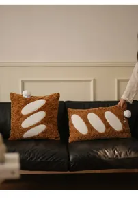 Coussins en peluche créatifs en forme de baguette sur un canapé en cuir noir