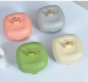 Aperçu de quatre boîtes de rangement pour bijoux portables multicolores avec poignées dorées