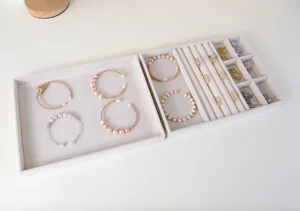 Vassoio portagioie in velluto beige con scomparti per anelli, bracciali e orecchini.
