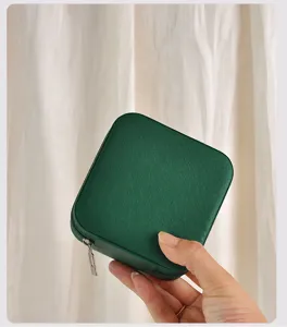 Detailweergave van het getextureerde groene vierkante juwelendoosje voor op reis.