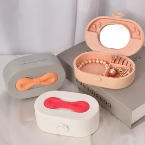 Boîte à bijoux portable avec poignée en nœud, miroir et divers compartiments.