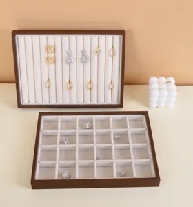 Elegantes bandejas para joyas de nogal con forro de terciopelo blanco y celdas.