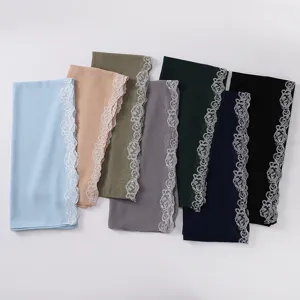 Presentación de varios hiyabs de gasa de colores con elegantes bordes de encaje de rosas