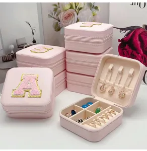 Detalle del interior del joyero rosa con ganchos para collares y ranuras para anillos