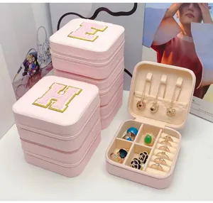 Detalle del joyero rosa con letra bordada y compartimentos de almacenamiento interno