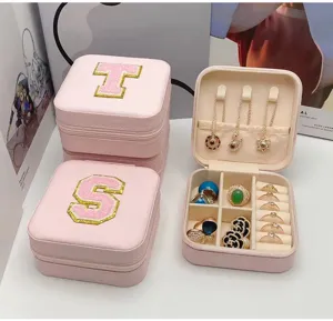 Detalle de caja de joyas de PVC rosa con bordado de letras universitarias y cremallera