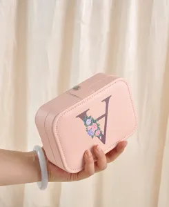 Primer plano detallado de un joyero de cuero PU rosa con un diseño floral de letra 'V'