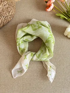 Detailed macro view of fresh green bow print on a lightweight cotton linen scarf