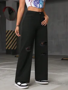 Detail of black ripped wide-leg jeans with a high-waisted distressed urban fit.