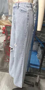 Detail view of light blue ripped wide-leg jeans on a mannequin in a warehouse.