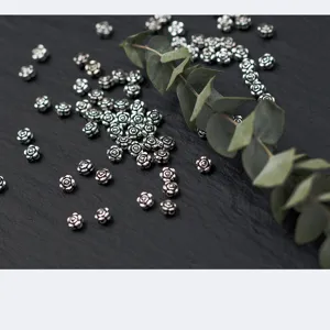 Vintage silver rose flower spacer beads for DIY jewelry making on dark slate background