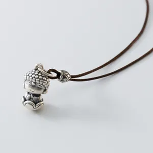 Detailansicht eines antiken Buddha-Anhängers aus Silber mit einer braunen Kordel.
