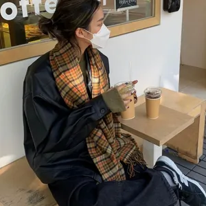 Écharpe à carreaux orange et noir stylisée sur un mannequin dans un café en plein air