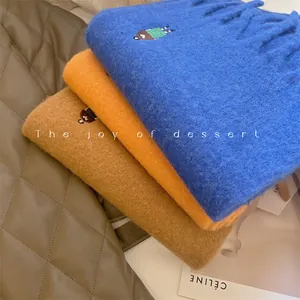 Macro view showing the soft texture and embroidery of colorful wool blend winter scarves.
