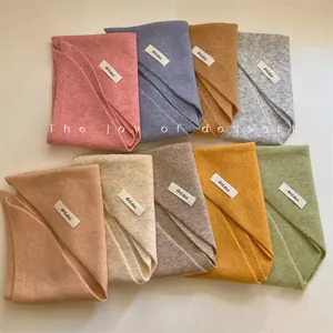 Close-up of wool blend solid color knit triangular scarves in multiple soft colors