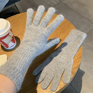 Nahaufnahme von weichen grauen Kaninchenfell-Strickhandschuhen auf einem Holztisch