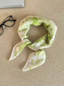 Detail view of the green and white cotton linen scarf featuring an elegant leaf pattern.