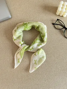 Detailed view of a light green floral cotton linen scarf on a textured beige surface