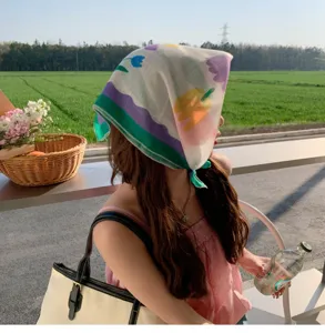 Stylish woman wearing a soft floral cotton linen square scarf as a headband in a field