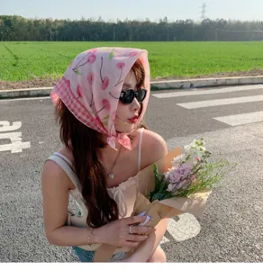 Outdoor view of pink cherry print cotton linen square scarf worn as a headscarf