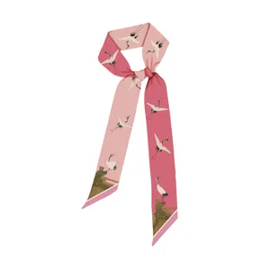 Dettaglio del foulard di seta rosa con eleganti motivi di gru e architettura.