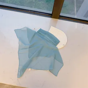 Detail showing the light blue chiffon sun veil with adjustable ear loops on a flat surface