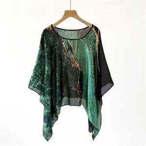 Detail of abstract printed faux silk poncho with green and gold artistic patterns