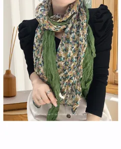 Close-up of green floral pleated cotton scarf showing delicate texture and pattern.