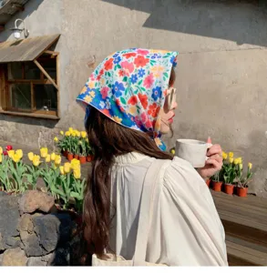 Detailed shot of a colorful floral cotton linen headscarf worn in a sunny outdoor setting.