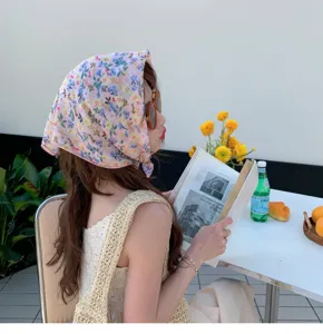 Close-up of a pink floral cotton linen headscarf worn by a model in an outdoor setting.
