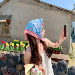 Floral blue cotton-linen square scarf worn as a headscarf in an outdoor setting