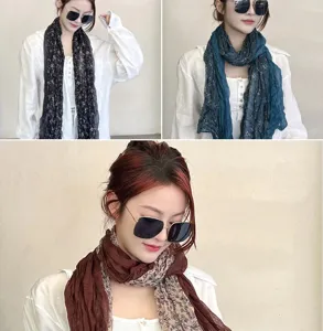 Detail view showing three colors of floral wrinkled cotton linen scarves worn by model