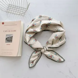Detailed view of the delicate floral pattern and green lace trim on this cotton scarf