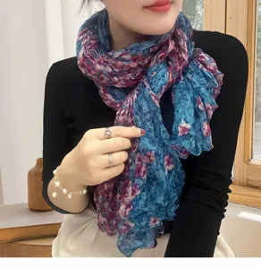 Close-up detail of a blue floral pleated cotton linen scarf worn as a stylish neck wrap.